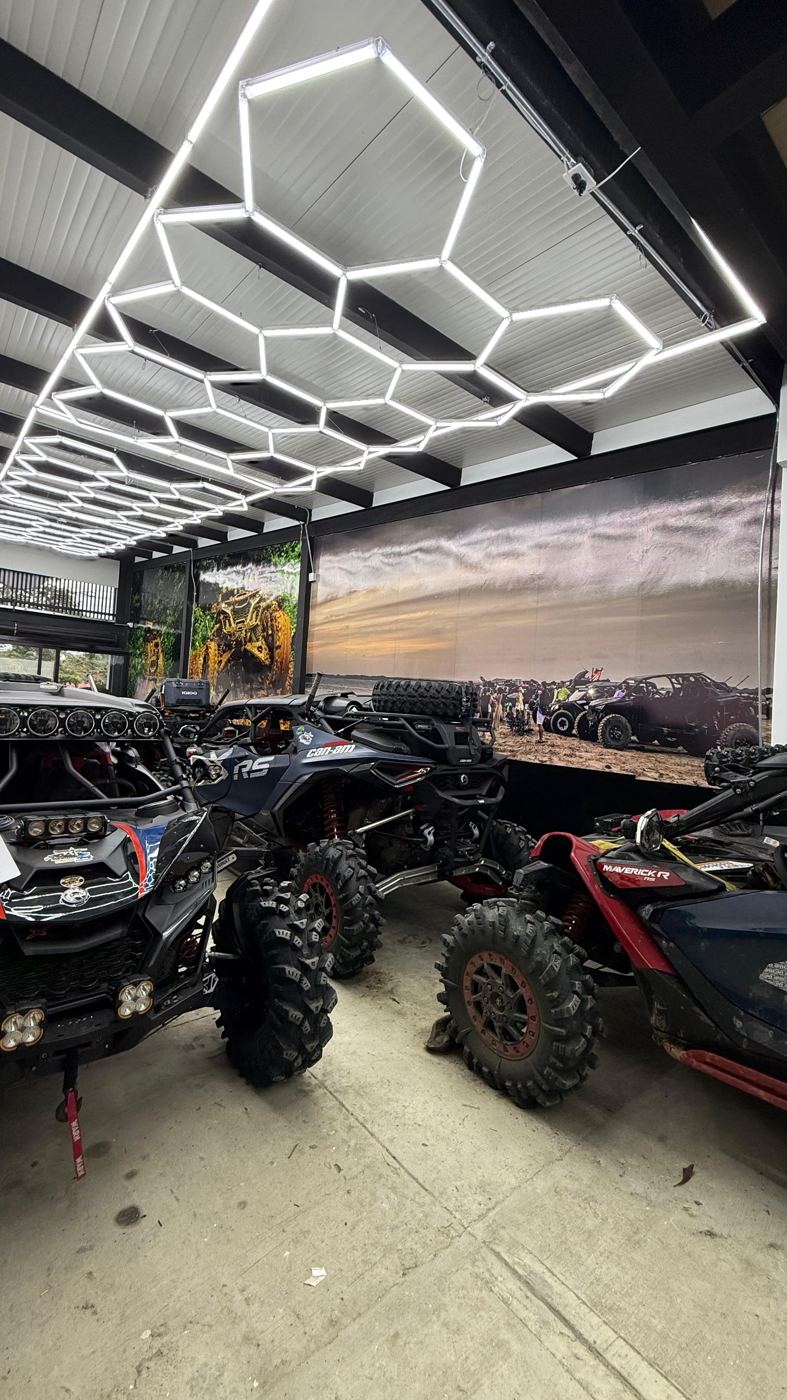 Interior del taller con techo de luces hexagonales y UTVs Can-Am